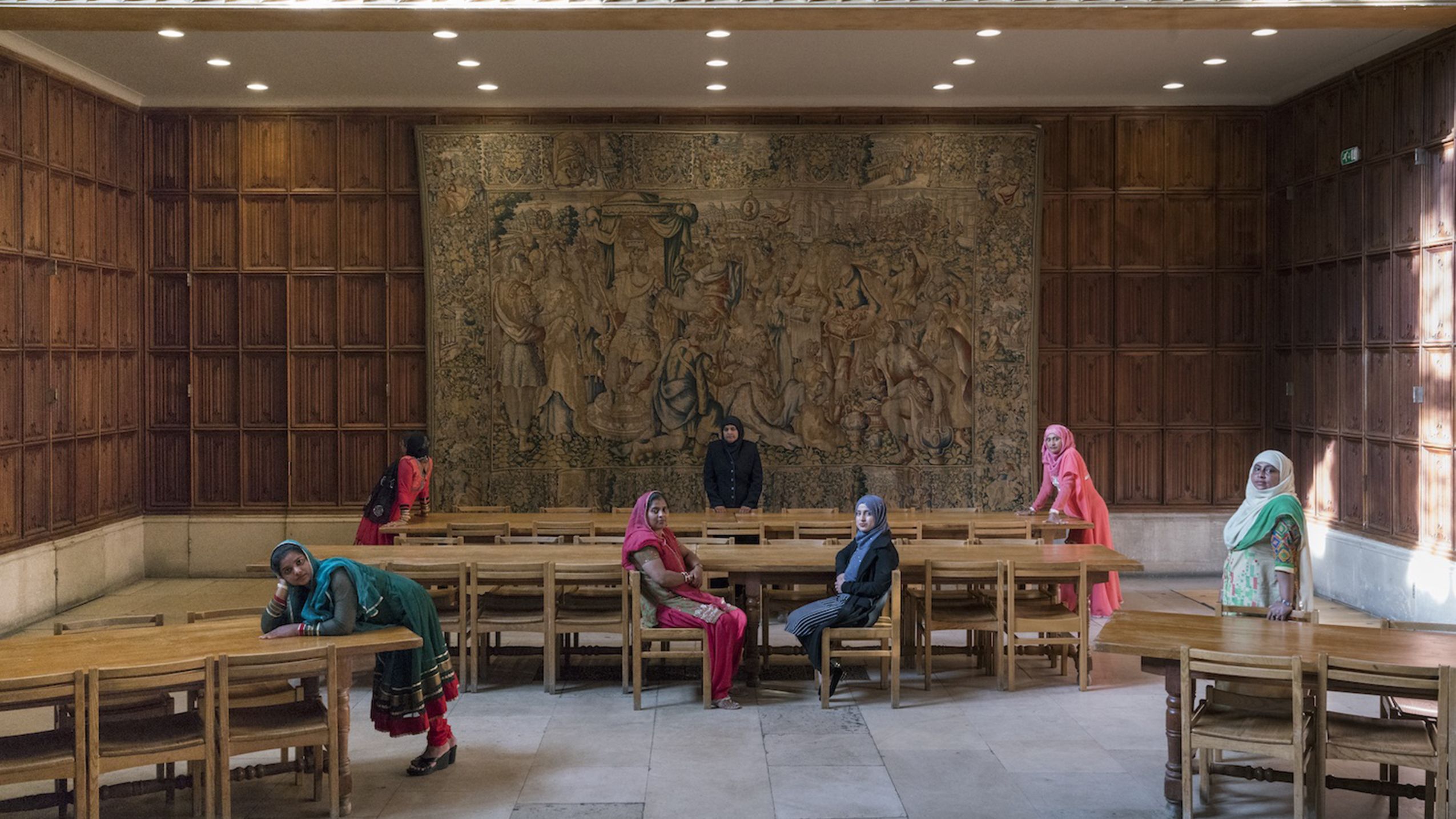 Photography by Melanie Manchot showing the ladies in colourful hijabs in the oak panelled King's College Dining Hall