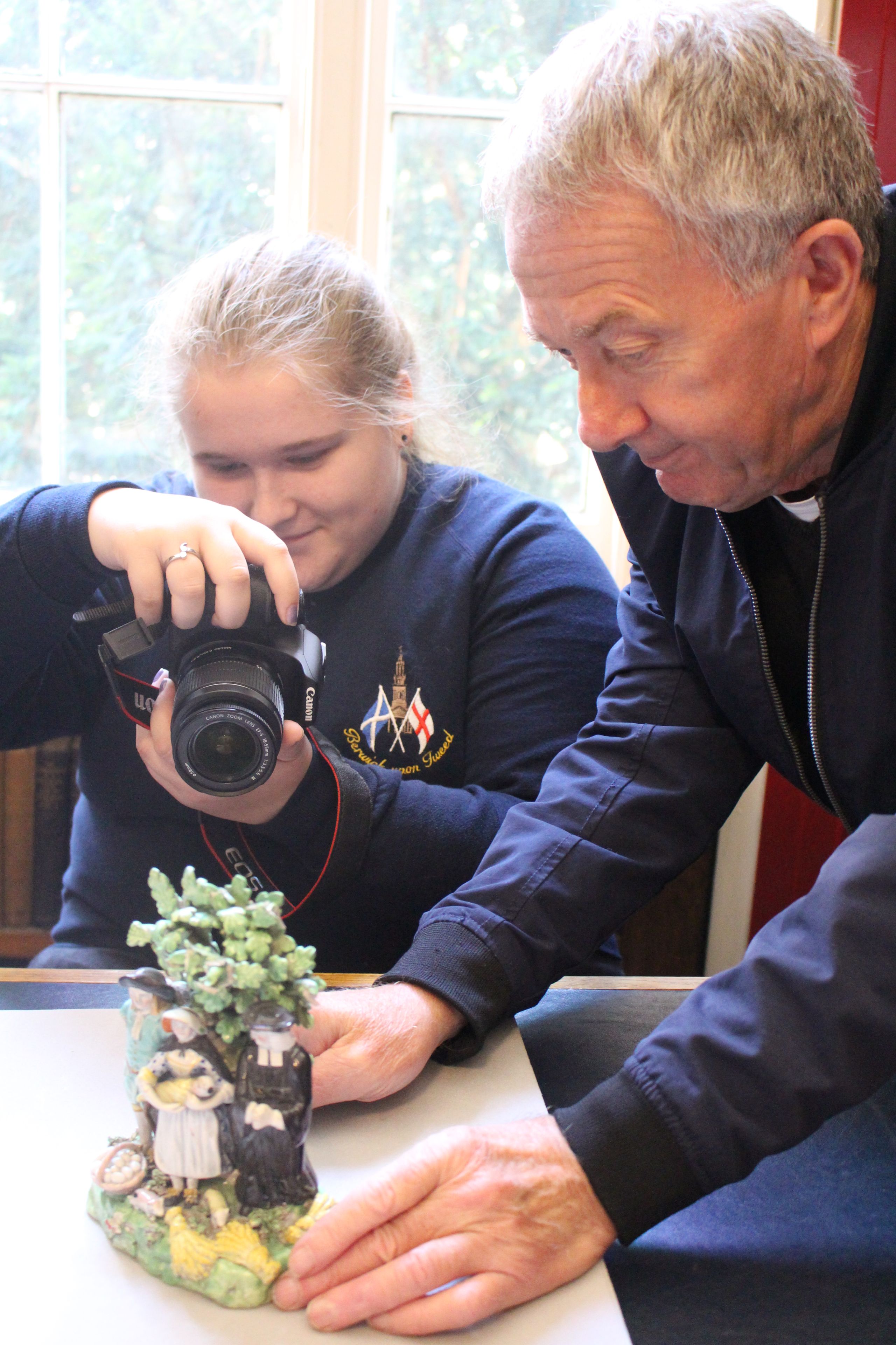 A girl photographs a ceramic object