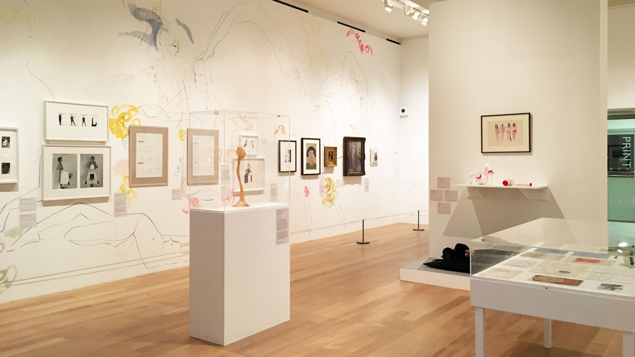 View of the exhibition, with a range of artworks and sculptures and a colourful mural on the wall