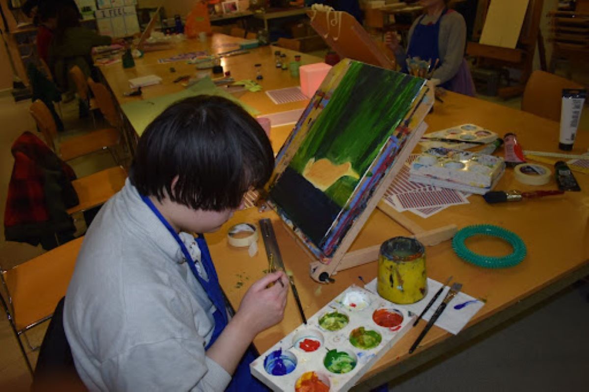 Child sits at a table with paints and craft materials