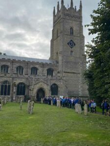 The St Andrew’s Soham church building with queue of schoolchildren entering.