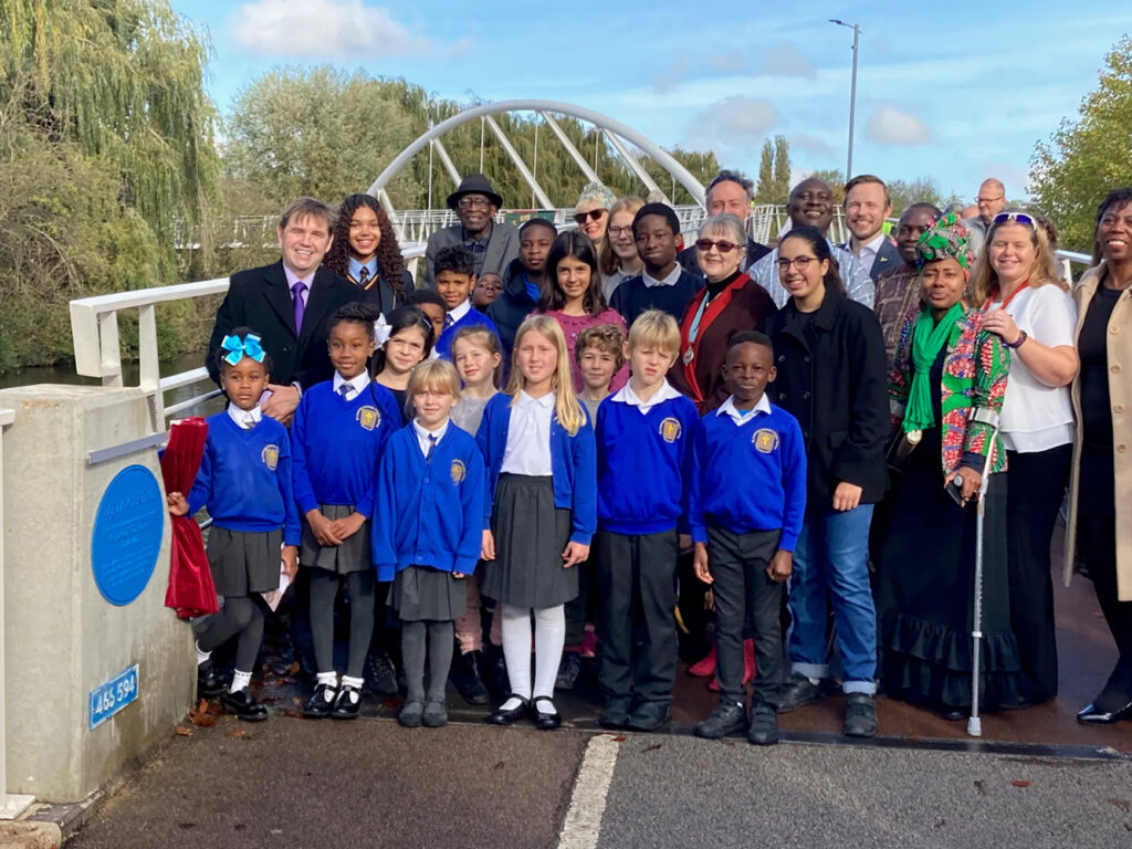 Soham primary school pupils, members of Cambridge African Network and Circles of Change, and local Chesterton residents at stand smiling on the Equiano Bridge at the launch.
