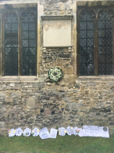 Anna Maria Vassa’s stone epitaph on the church wall surrounded by a white wreath of roses and other tributes by local schoolchildren.