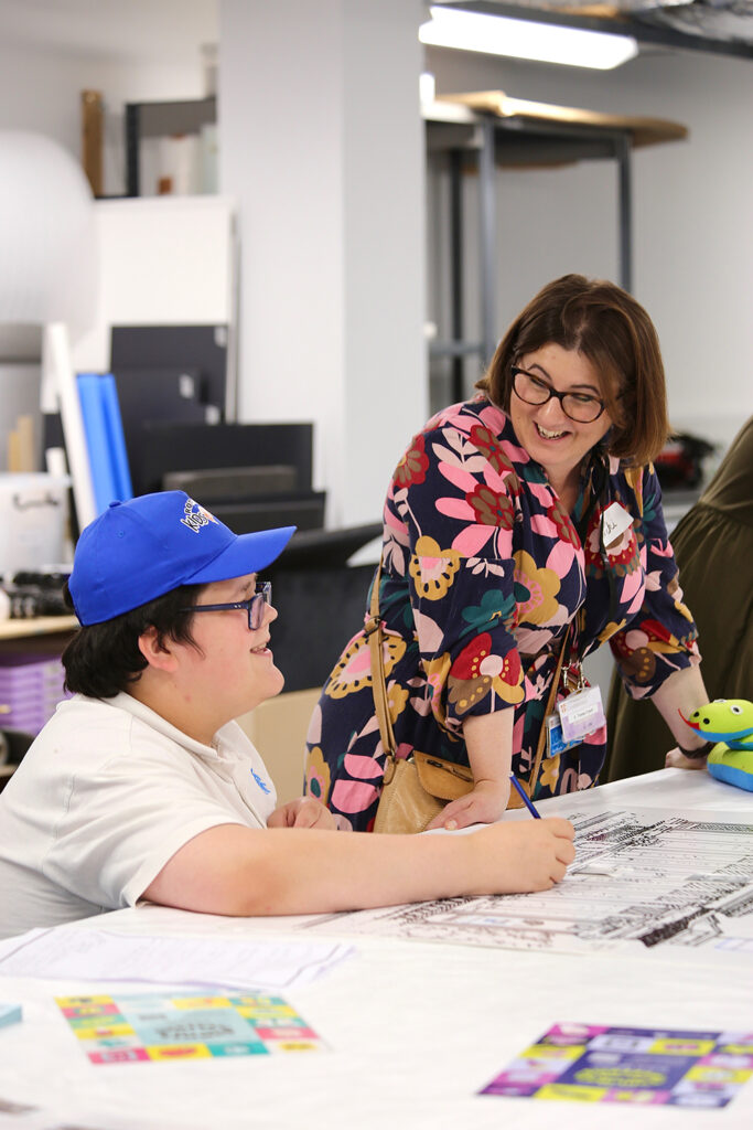 UCM's Niki Hughes stands speaking to a work experience participant sat at a desk in front of a Fitzwilliam Museum drawing.