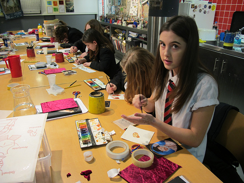 Students at a workbench in the Museum's studio use paints and craft materials to make their portraits