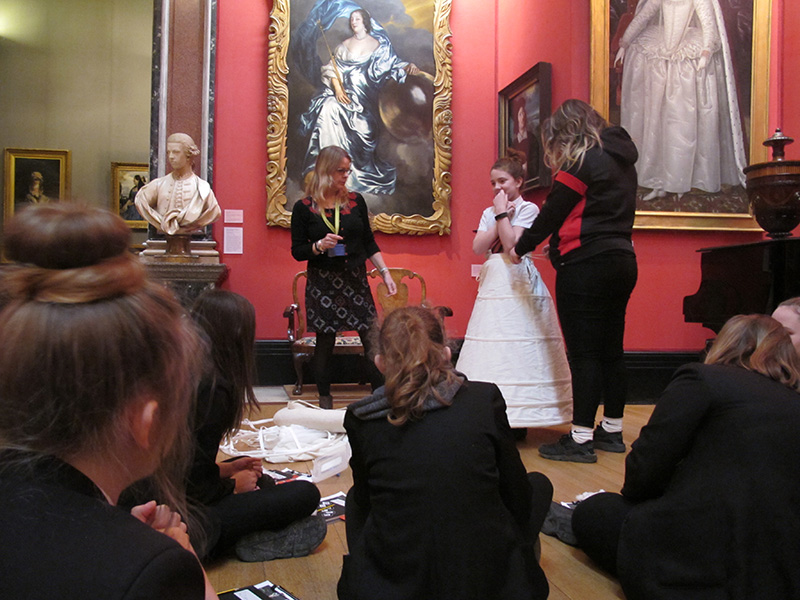 A student tries on a wide, white Elizabethan underskirt