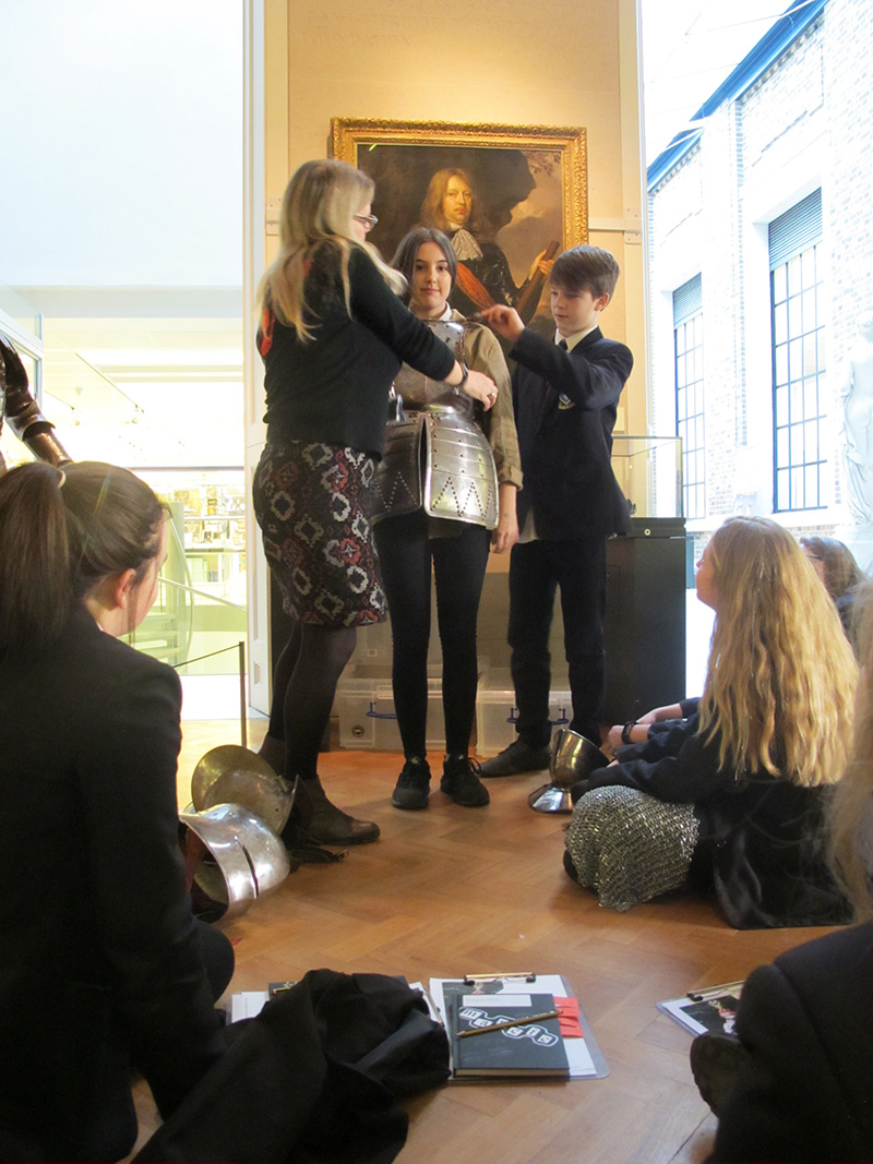 Secondary school students try on armour in the museum's Armoury