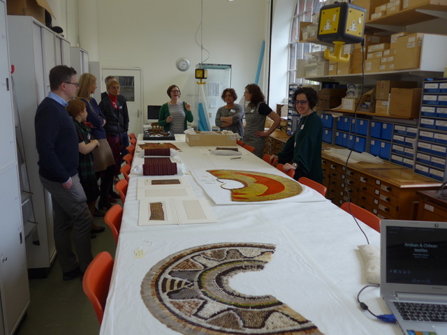 A group of researchers discuss textiles objects in the Museum workroom 