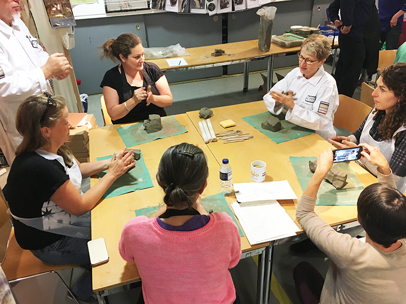 Participants working with clay around a table in the studio