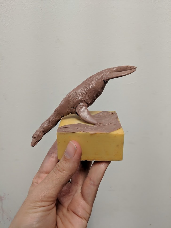 a small clay maquette with the dinosaur posed as if diving