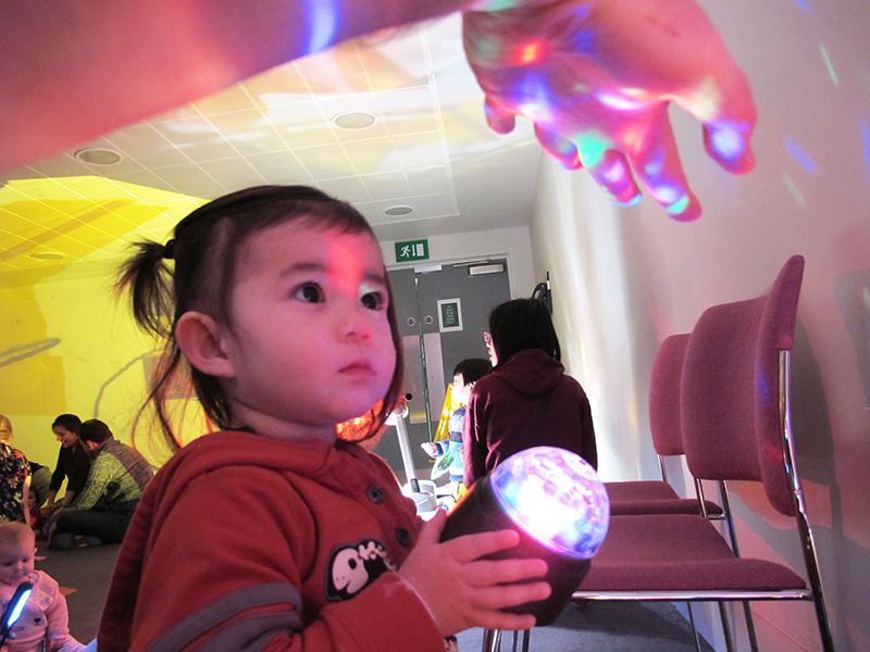 a toddler explores the lights and shapes created by a disco ball