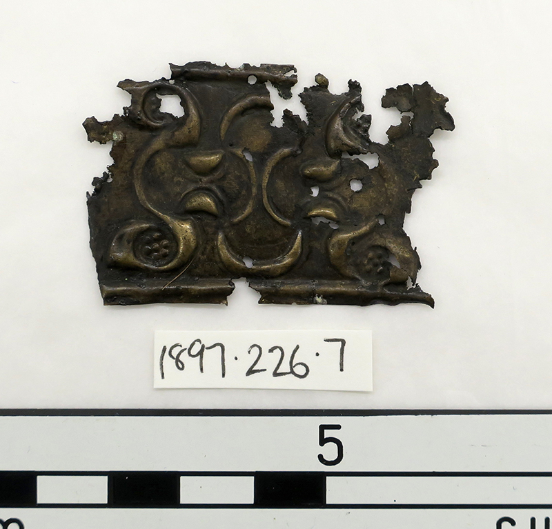 A small bronze object laid out against a measure