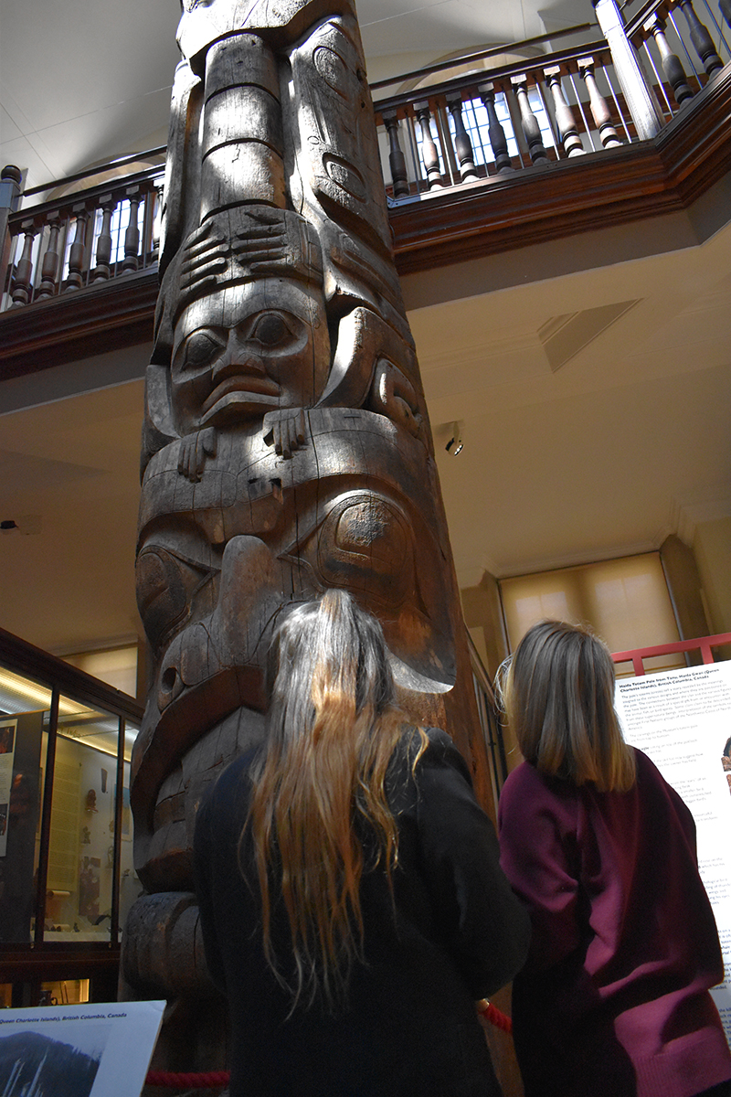 Two students looking at a totem pole in the Museum