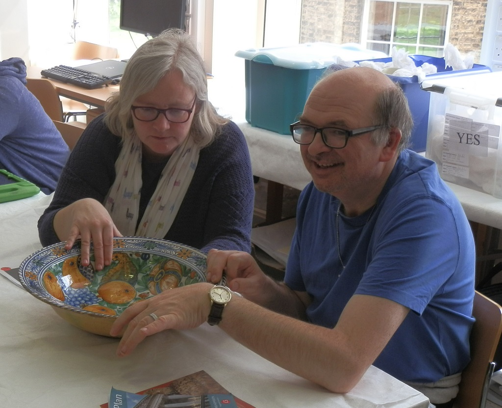 Sarah and Mark examining the vibrant decoration of the pomegranate charger, and the best angle for viewing it