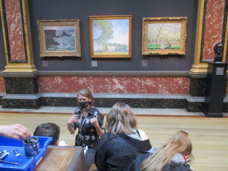 Young people seated in front of 3 Impressionist paintings at the Fitzwilliam Museum