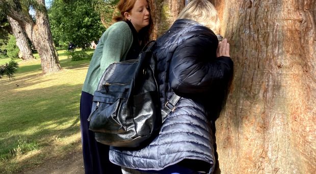 Young people standing with ears pressed to a tree