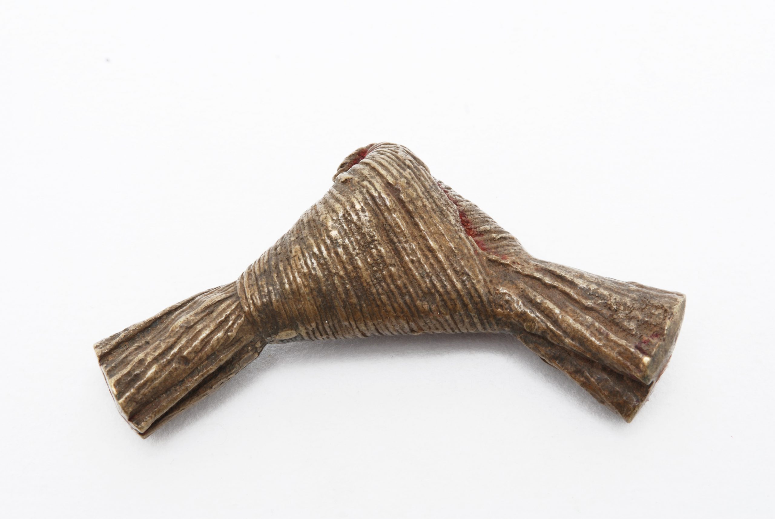 A brass weight depicting a piece of knotted fibres.