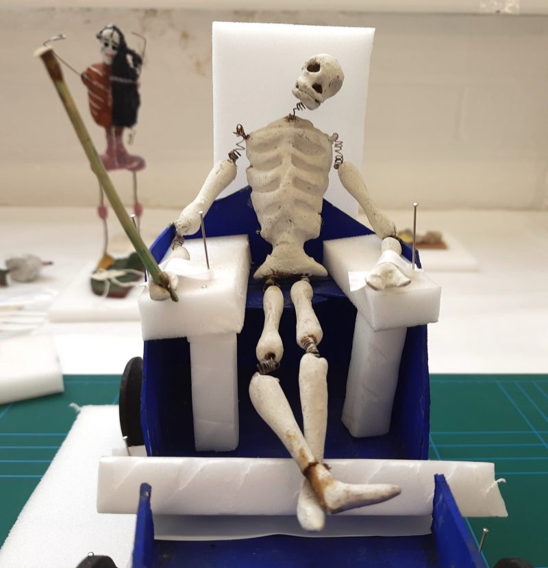 Clay and spring model of a skeleton in a wooden cart, supported with plastazote wedges and blocks, PTFE tape and pins