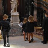 3 young people walking down stone steps in the Fitzwilliam Museum. The lower half of a classical statue is at the bottom of the stairs