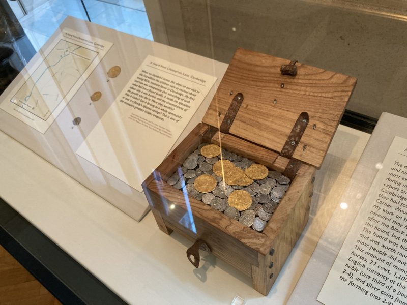 Display cabinet showing small wooden chest filled with gold and silver coins
