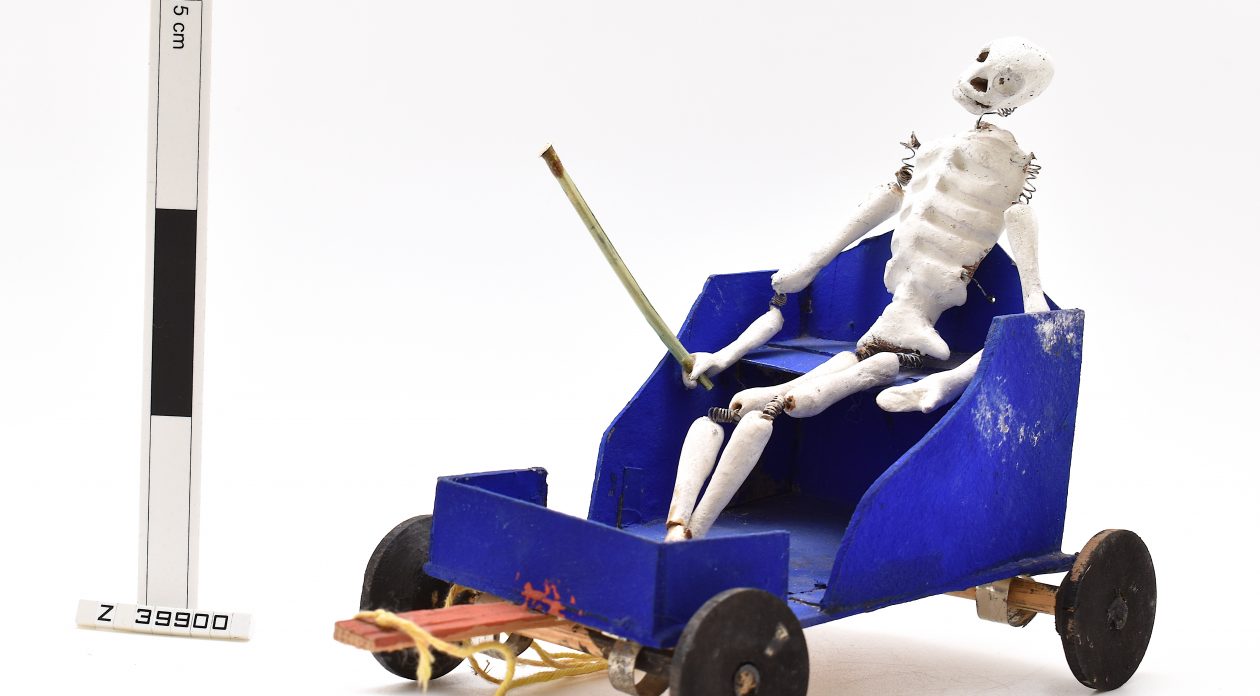 Model of a skeleton sitting in a blue cart, used as part of the Day of the Dead celebrations