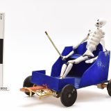 Model of a skeleton sitting in a blue cart, used as part of the Day of the Dead celebrations