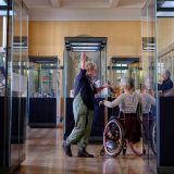 Group of older people - one in a wheelchair - in ceramics gallery of the museums surrounded by glass display cabinets