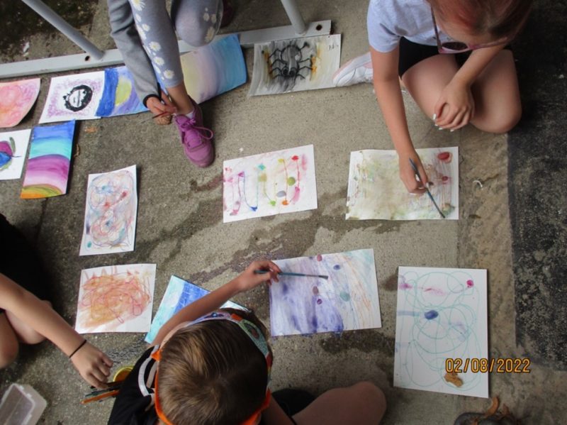 Young people kneeling on the ground painting