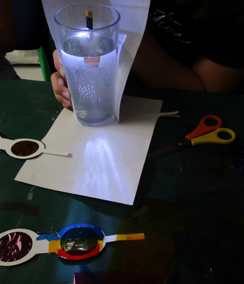 Glass of water lit up from behind to illustrate how light is composed of different colours.