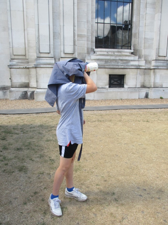 Child standing on lawn outside museum using a hand-made camera obscura