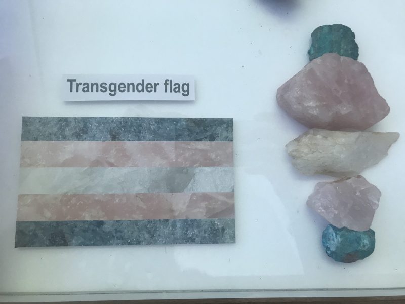 Image of exhibition display featuring transgender flag alongside rock samples in similar colours