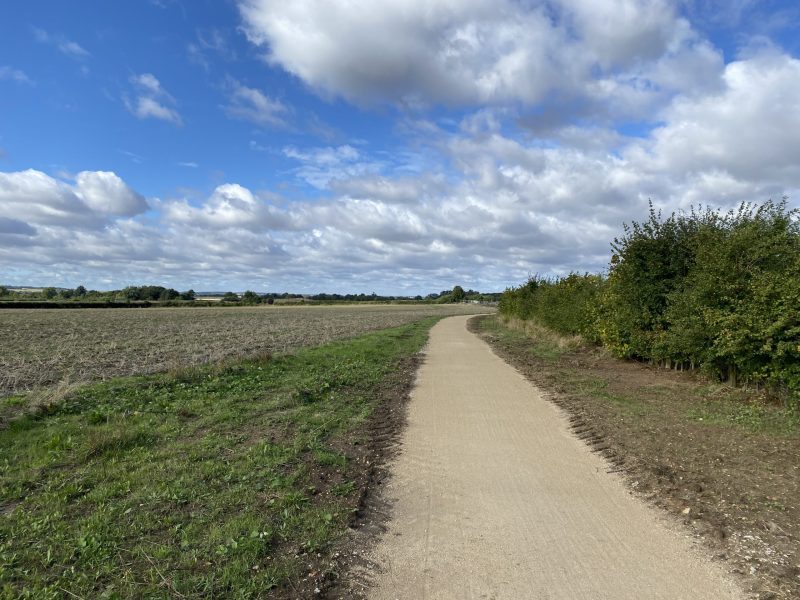 Chalk path across a field with blue sky and clouds above