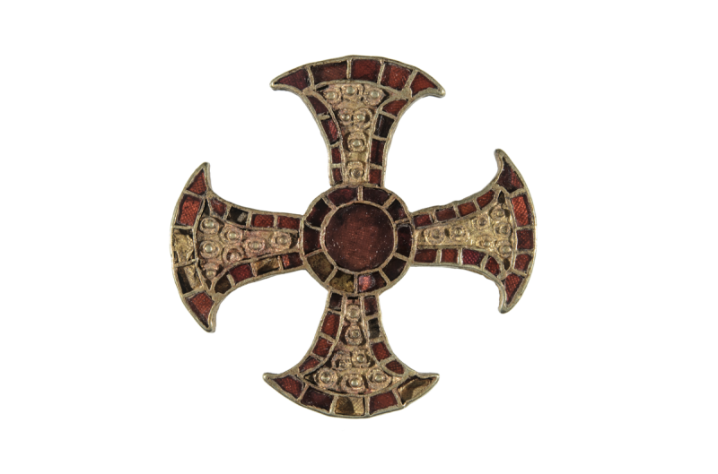 An ornate gold cross against a white background decorated with red garnets.