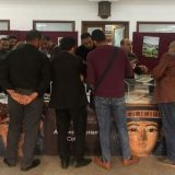Pop-up museum stall in Damietta Public Library Egypt. A group of local men and women stand at the stall with their backs to the camera.