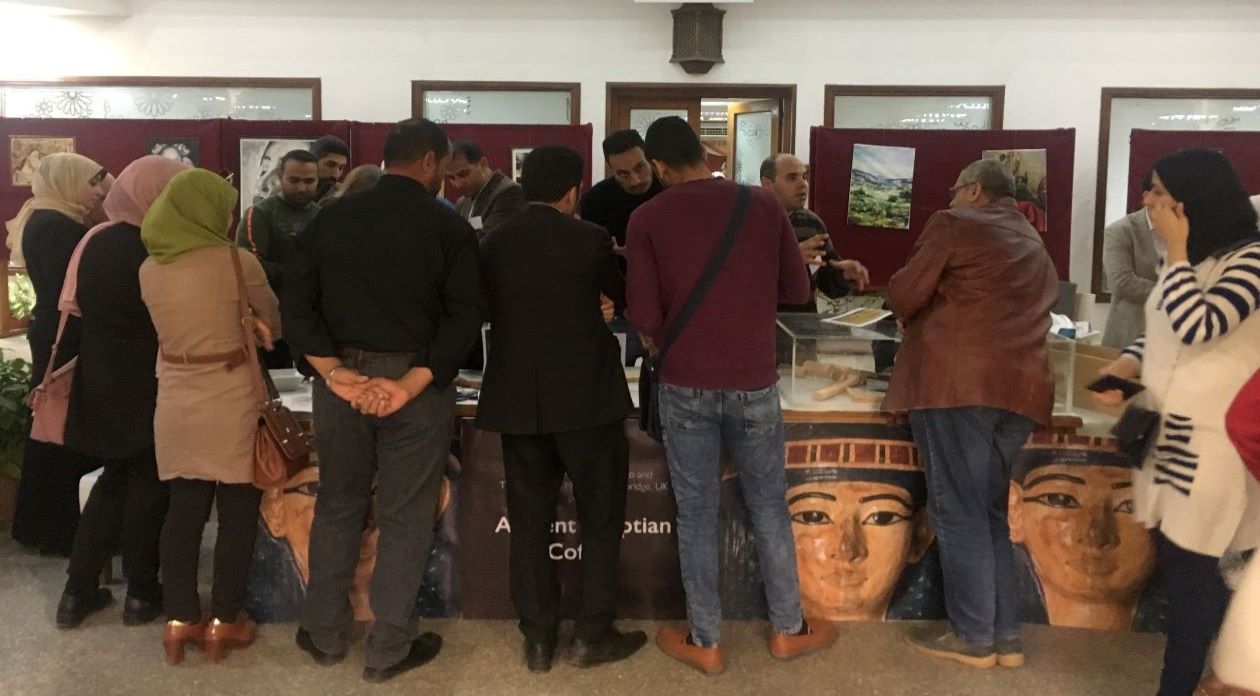 Pop-up museum stall in Damietta Public Library Egypt. A group of local men and women stand at the stall with their backs to the camera.