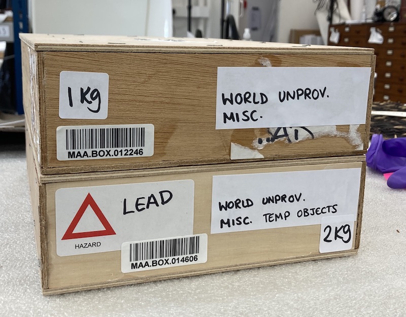 Two labelled woodedn boxes on top of each other. One has a lead hazard label