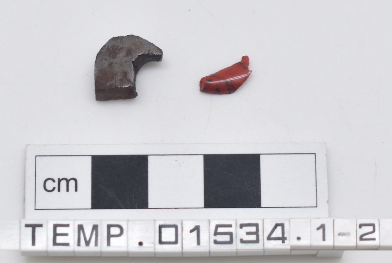 Two fragments, one of metal and one of red glass.