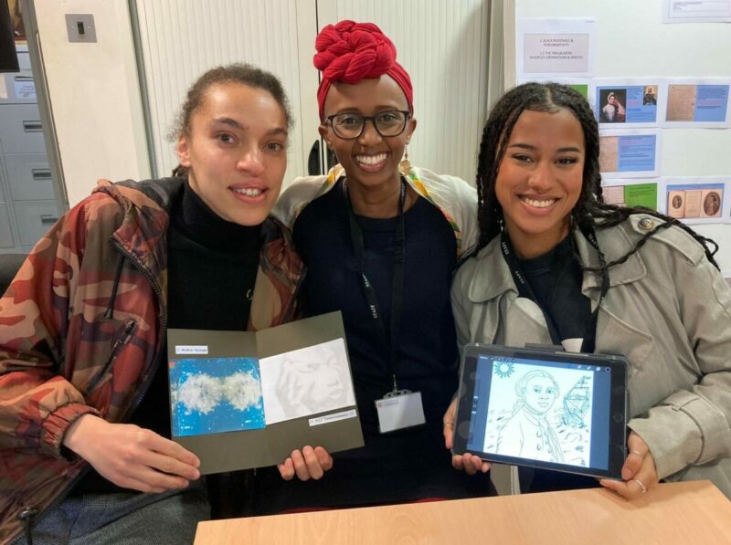 3 woman of colour pose for the camera while holding examples of their illustrations