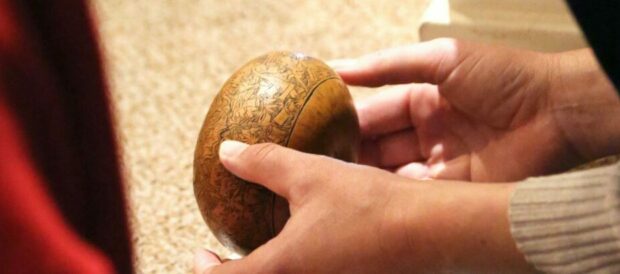 Pair of hands holding a small wooden globe