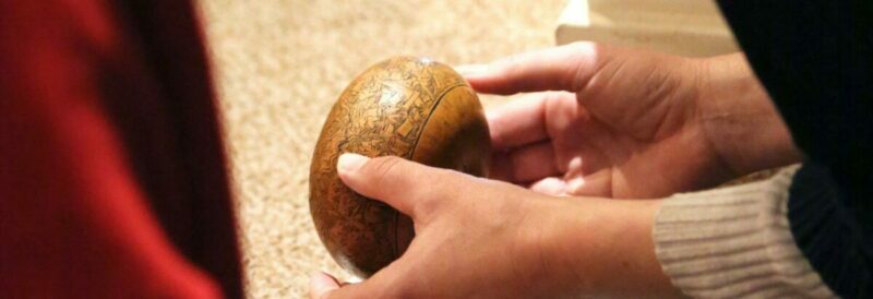 Pair of hands holding a small wooden globe