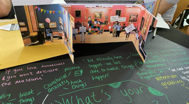 Paper model of a museum standing on a table featuring comments written by participants