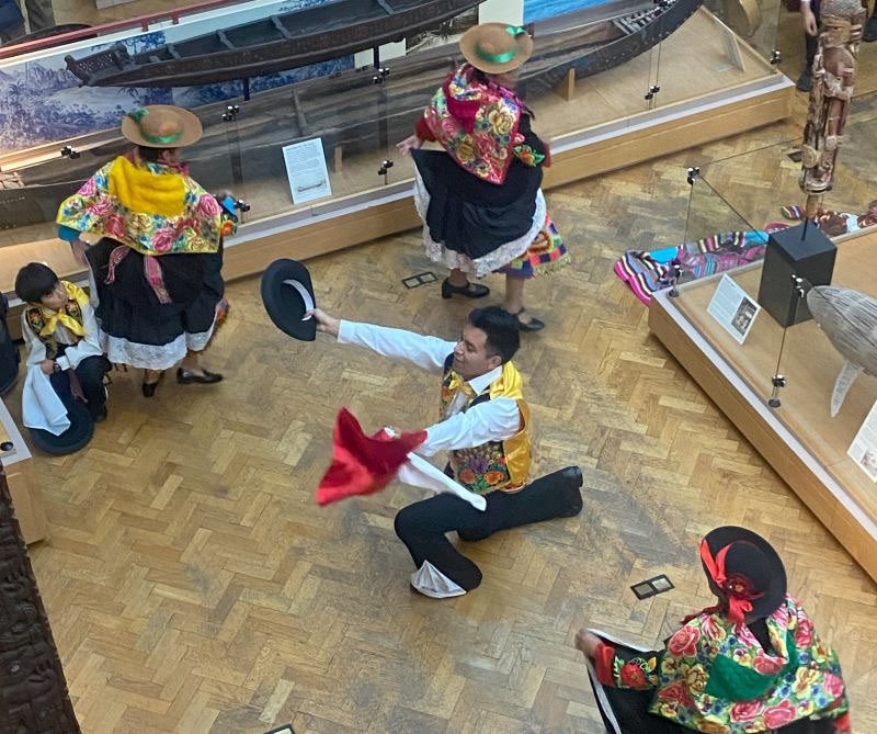 Image taken from above of 4 traditional dancers from Peru performing in the gallery space