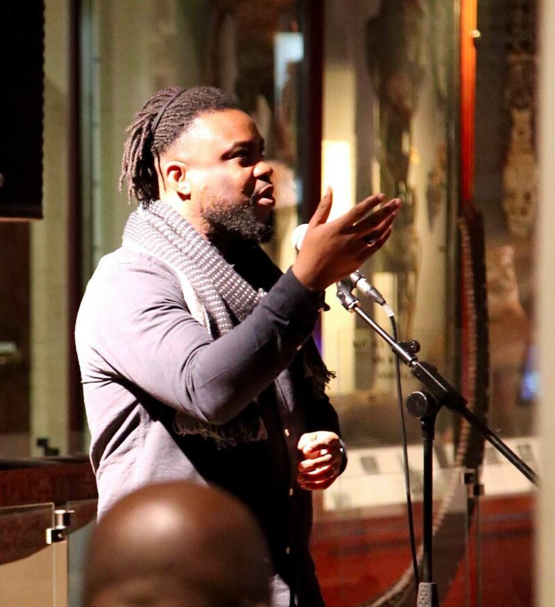 A Black male stands in front of a microphone 