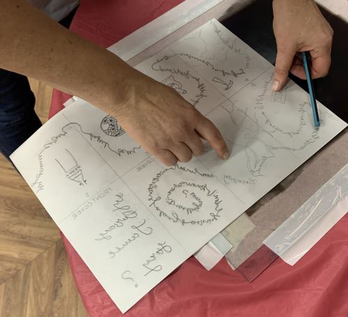 A hand points to a series of sketches mapping out a 'Zine' story on paper