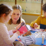 A woman with two children sit at a table at the Fitzwilliam Museum and create their own museum collage.