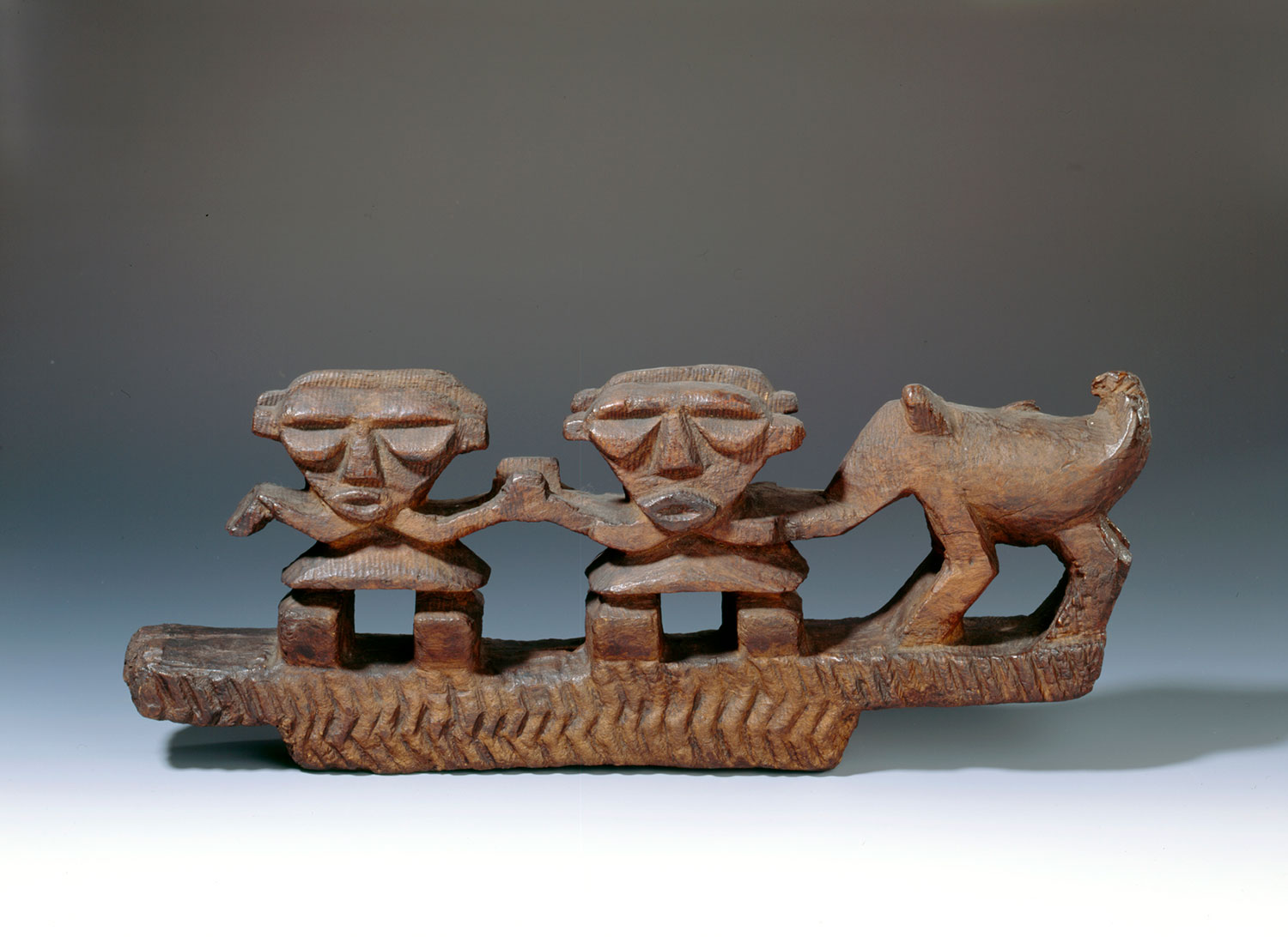 Lintel or prow ornament representing a pair of conventionalised human figures and a dog