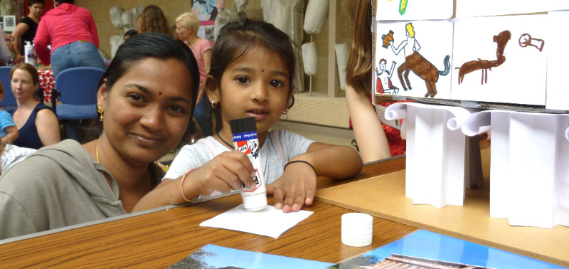 A mother and child doing crafts in a museum gallery.