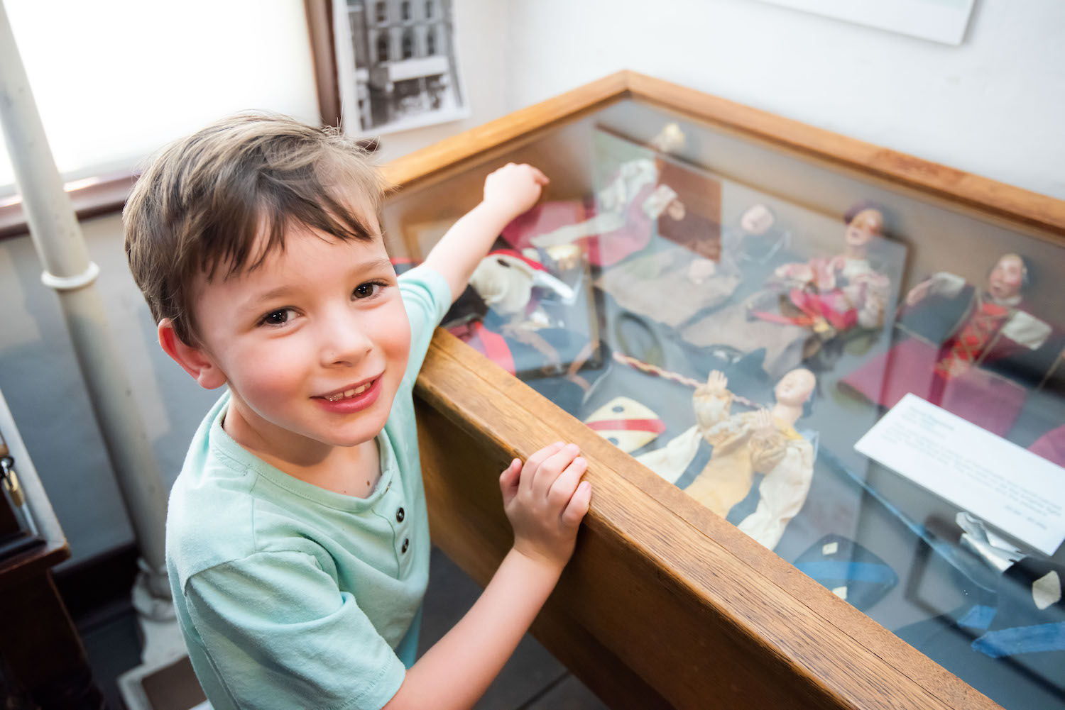 Little boy looking at a glass case of objects