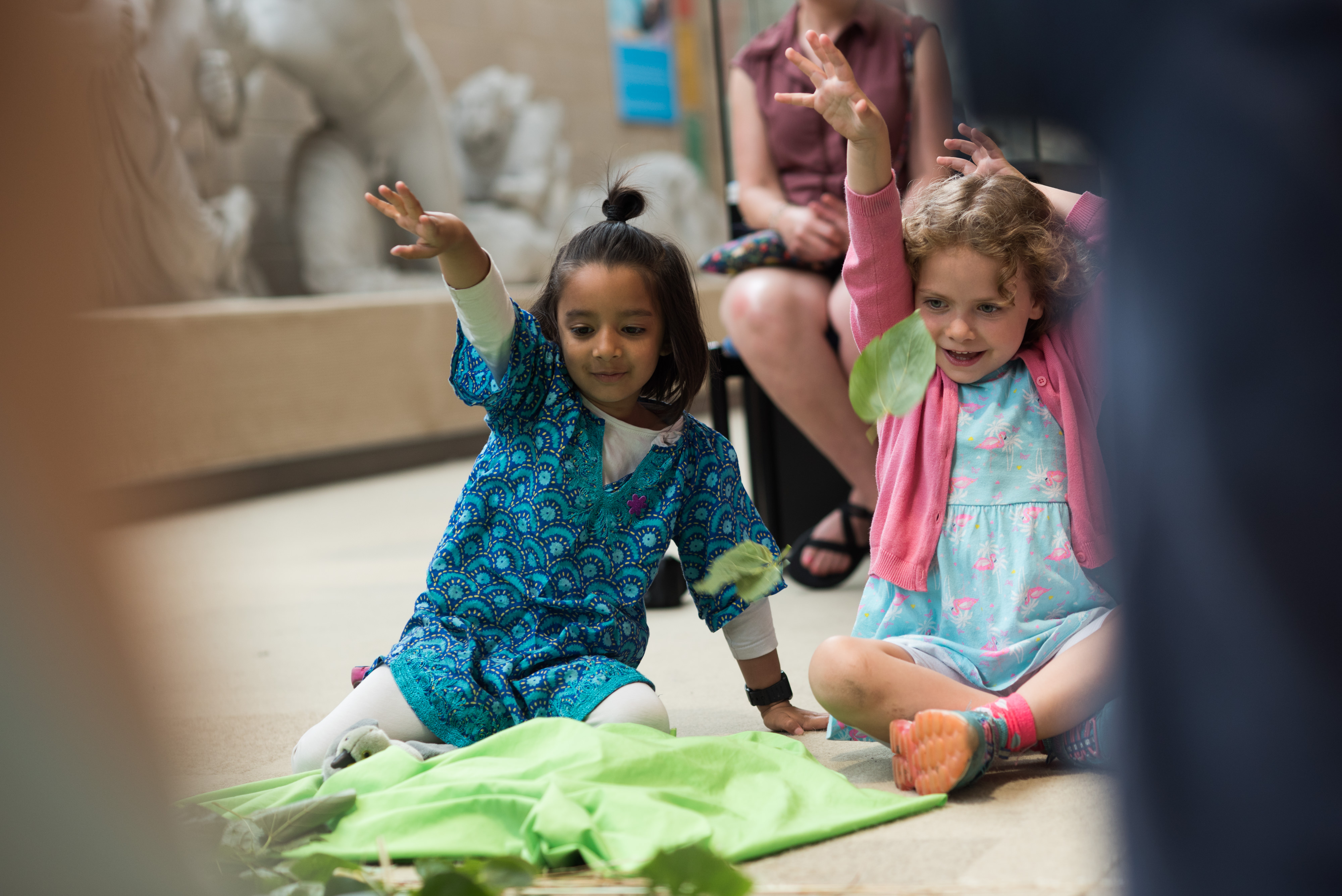 Two children sitting and playing on the floor of a museum gallery.