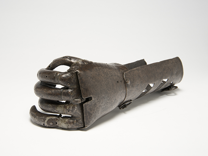 iron prosthetic hand viewed from the fist end, showing the articulation of the finger joints at the knuckle and their attachment to the smooth back of the hand